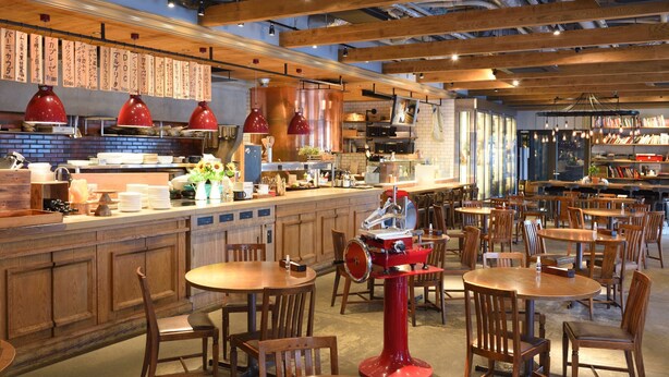 Ein Restaurant mit Holztischen und -stühlen, einer Küchenzeile und hängenden Speisekarten.