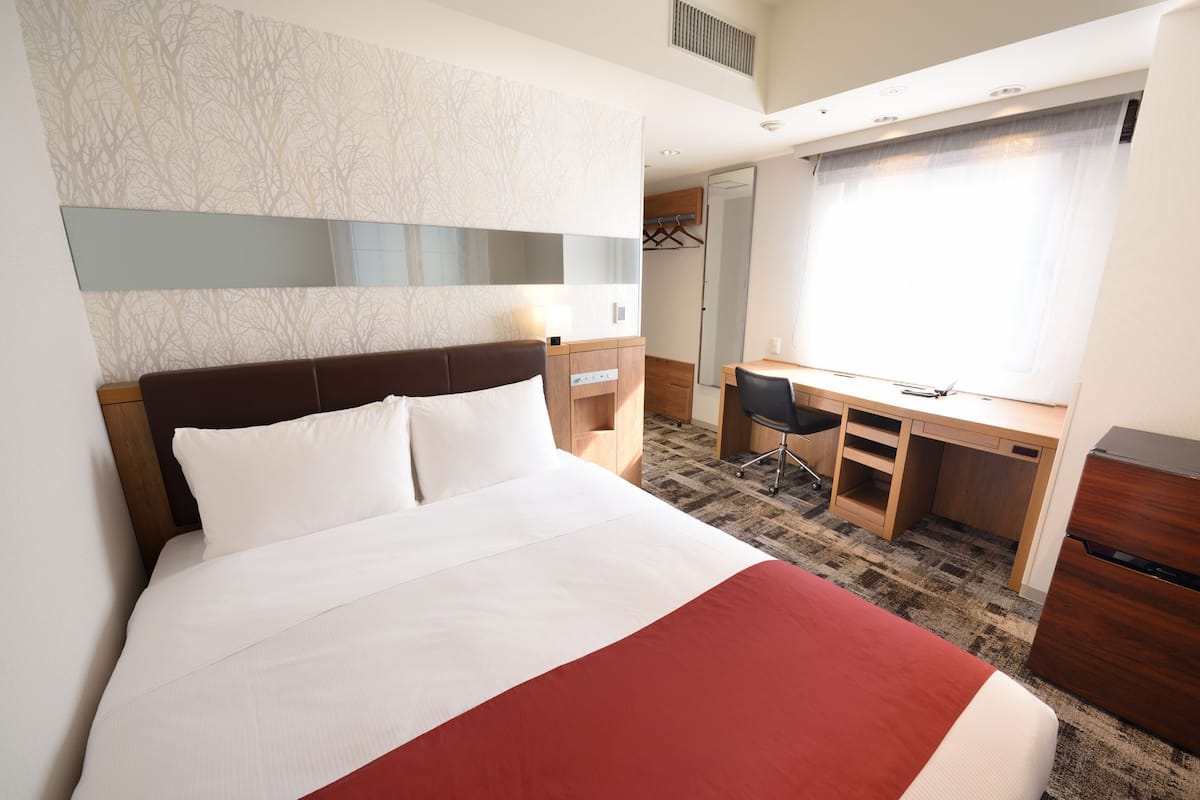 Ein Hotelzimmer mit einem großen Bett, einem Schreibtisch und einem Spiegel.
