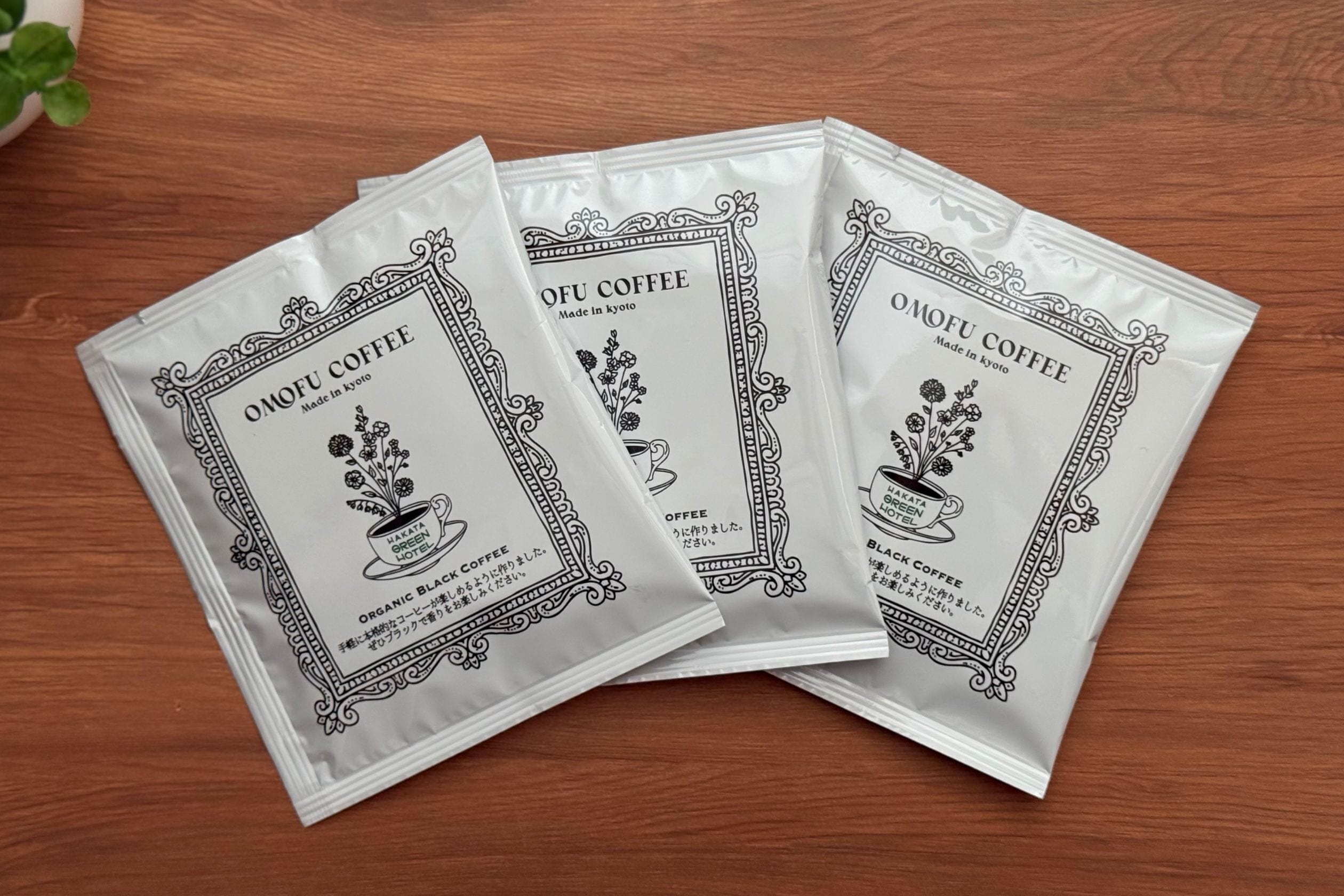 Three packets of Omofu Coffee on a wooden surface.