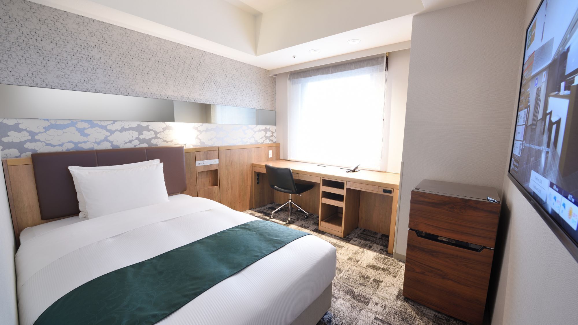 Une chambre d’hôtel comprenant un lit, un bureau, une chaise, une télévision et une armoire.