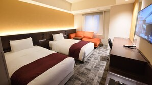 Ein Hotelzimmer mit zwei Betten, einem Schreibtisch und einem Fernseher.