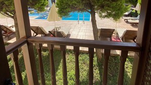 A wooden deck with a view of a swimming pool, lounge chairs, and a pergola. - Hotel Oludeniz (Fethiye)