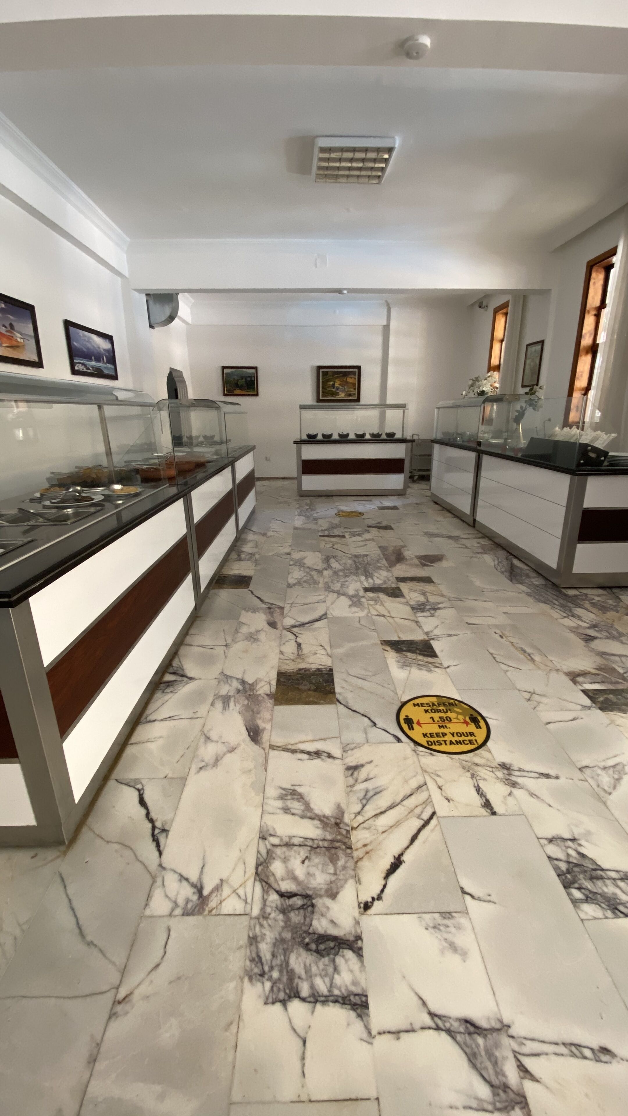 A modern kitchen with marble flooring, a central island, and a glass display case.