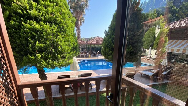 A balcony with a view of a swimming pool, a pergola, and a patio area with outdoor furniture. - Hotel Oludeniz (Fethiye)