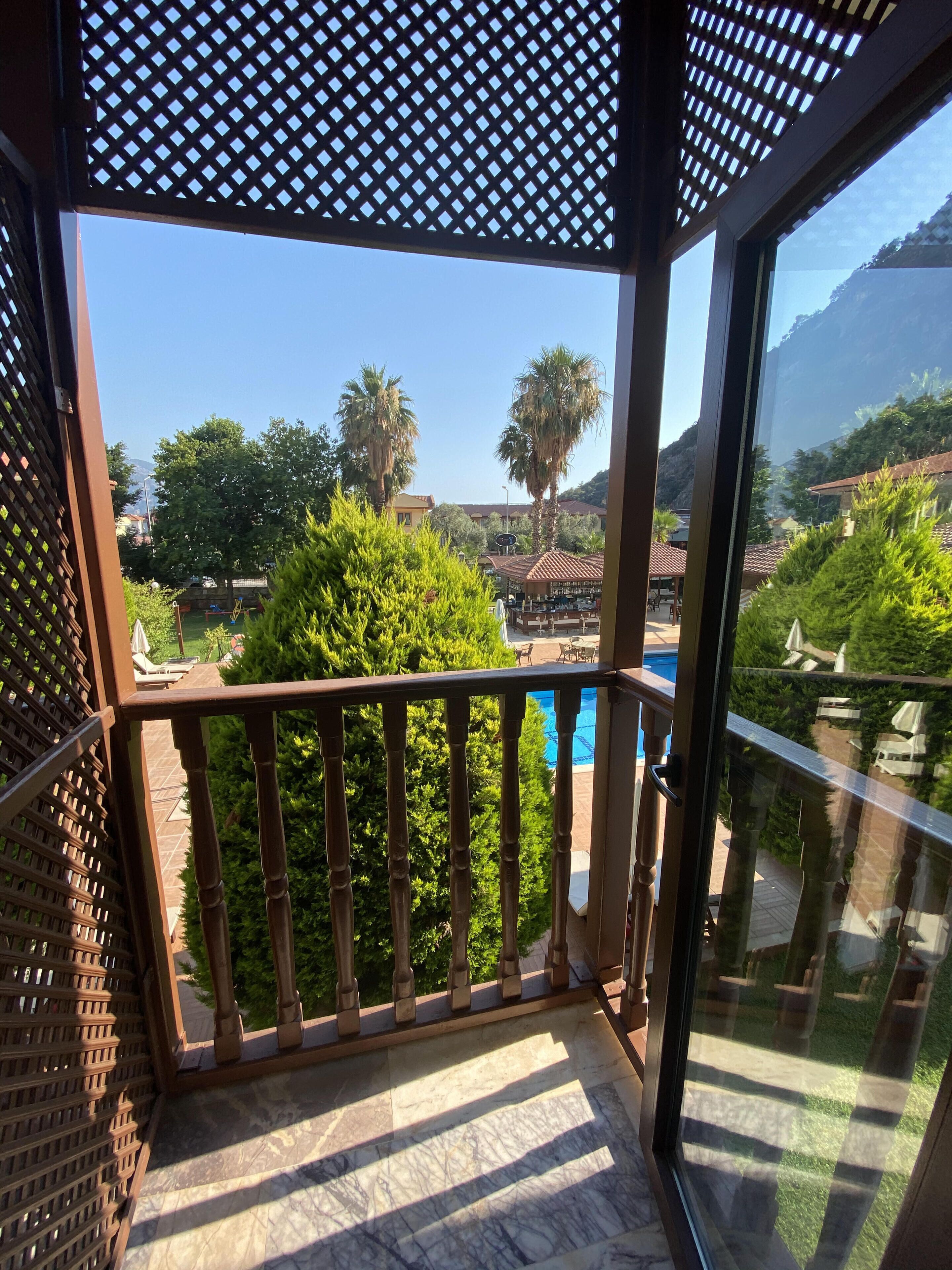 Un balcon offrant une vue sur une piscine, des palmiers et un paysage montagneux.
