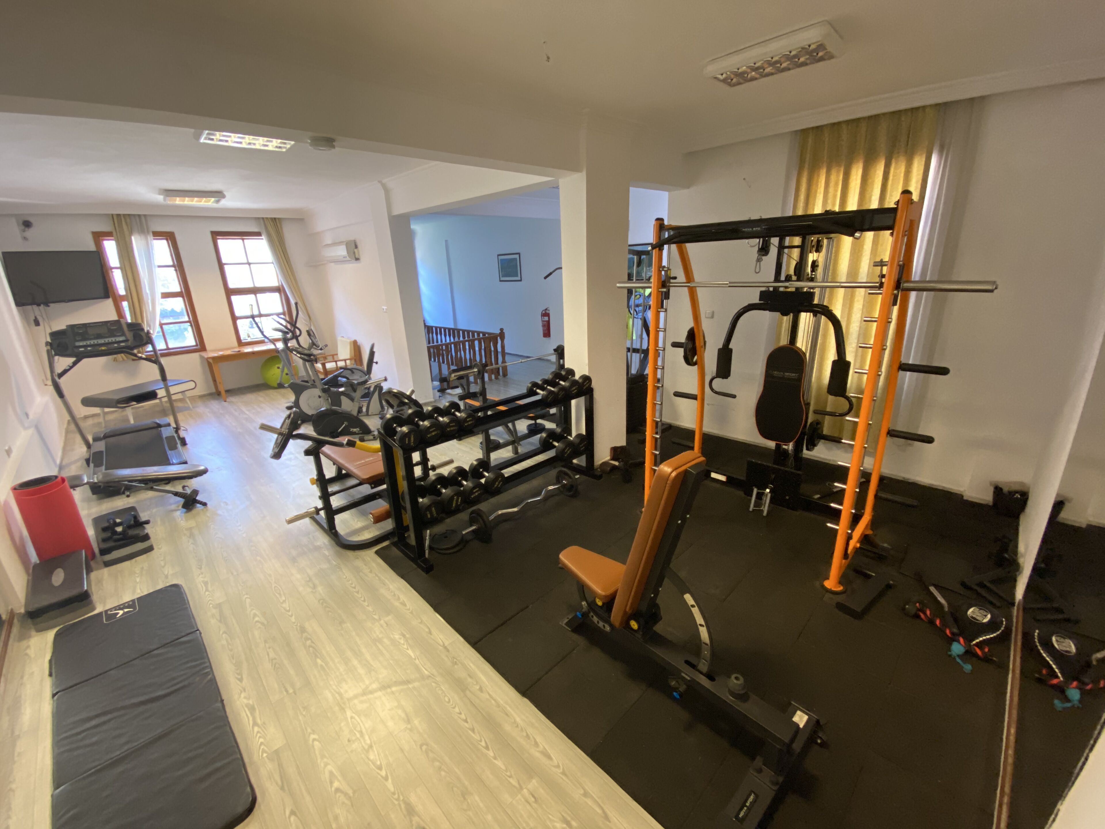 A gym with exercise equipment, a bench, and a treadmill.
