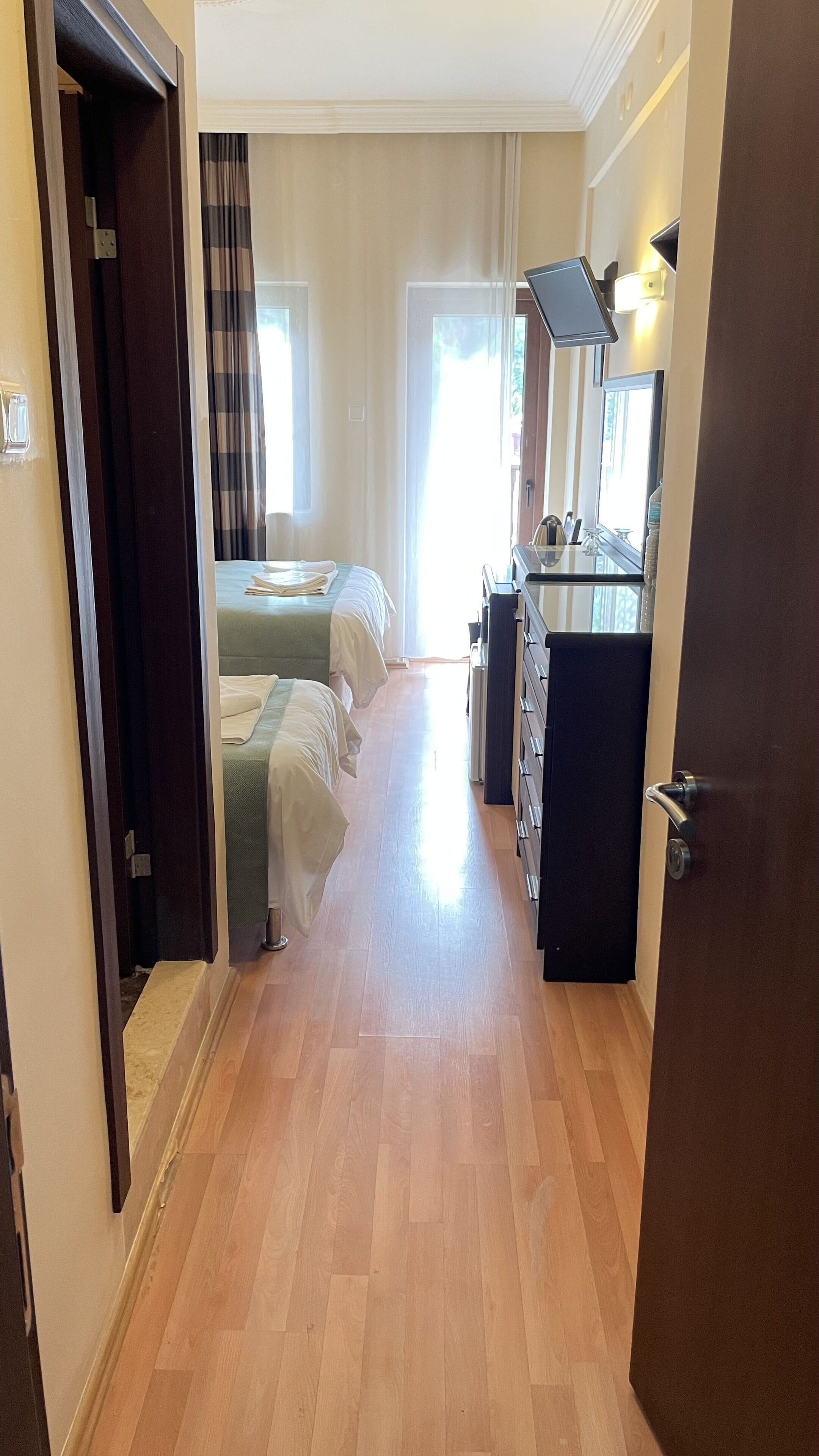Une chambre d’hôtel avec un plancher en bois, un lit, un bureau et une chaise.