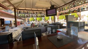 A bar area with a variety of liquor bottles, a television screen, and a QR code for a menu. - Hotel Oludeniz (Fethiye)