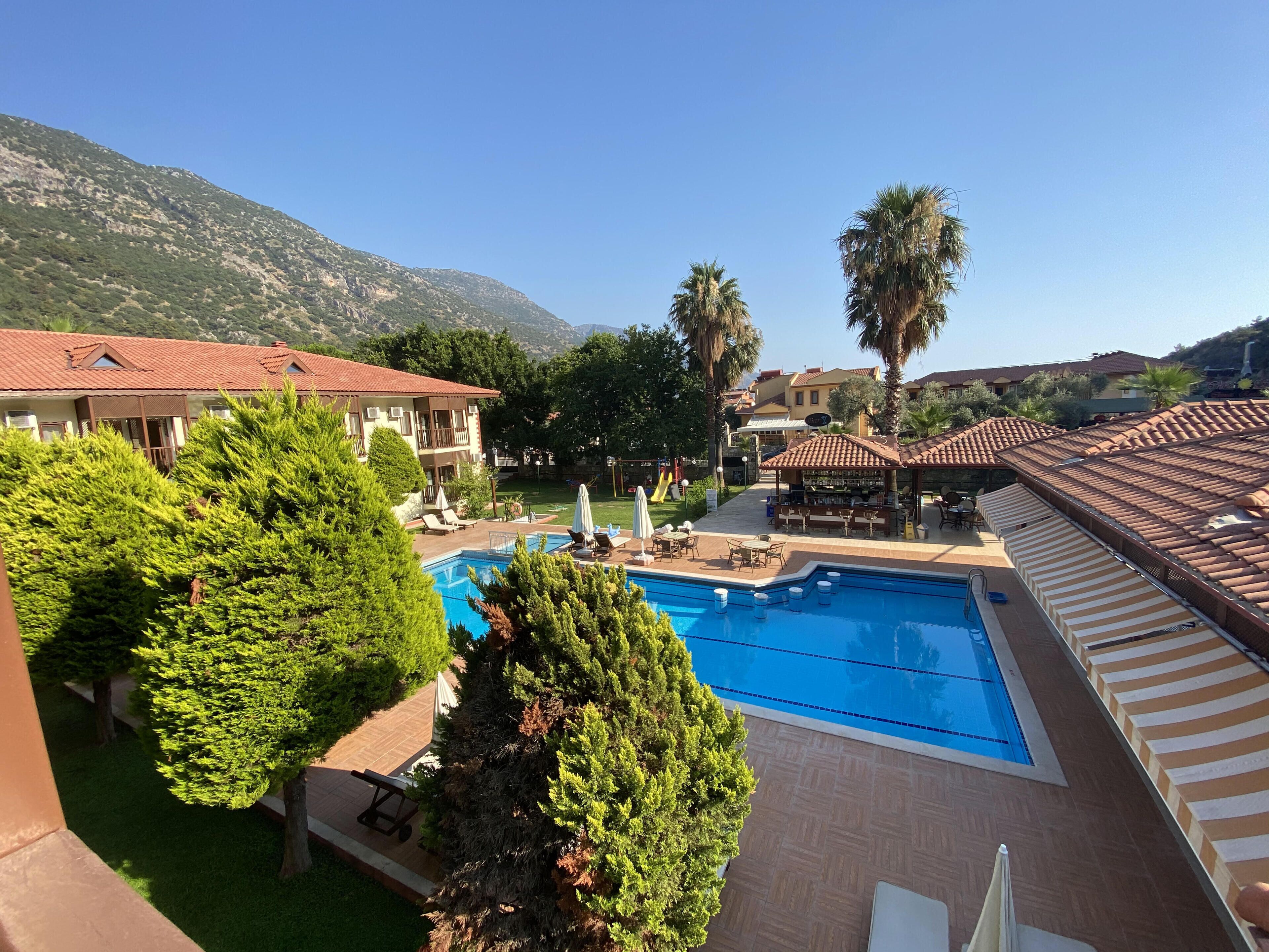 A resort with a swimming pool, lounge areas, and a view of the mountains.