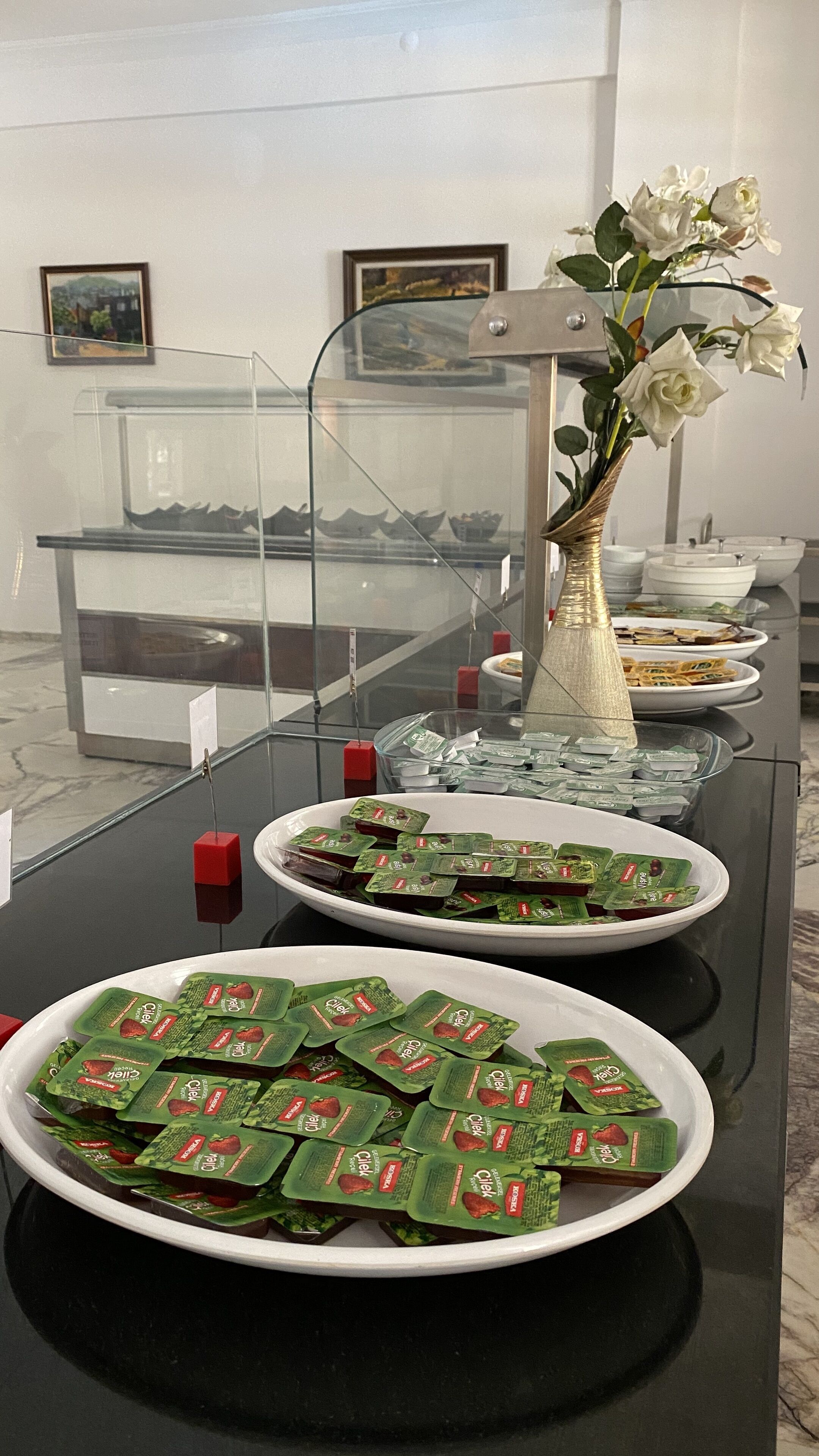Una mesa de buffet con diferentes alimentos, incluyendo cuencos de comida envasada y un florero con flores.