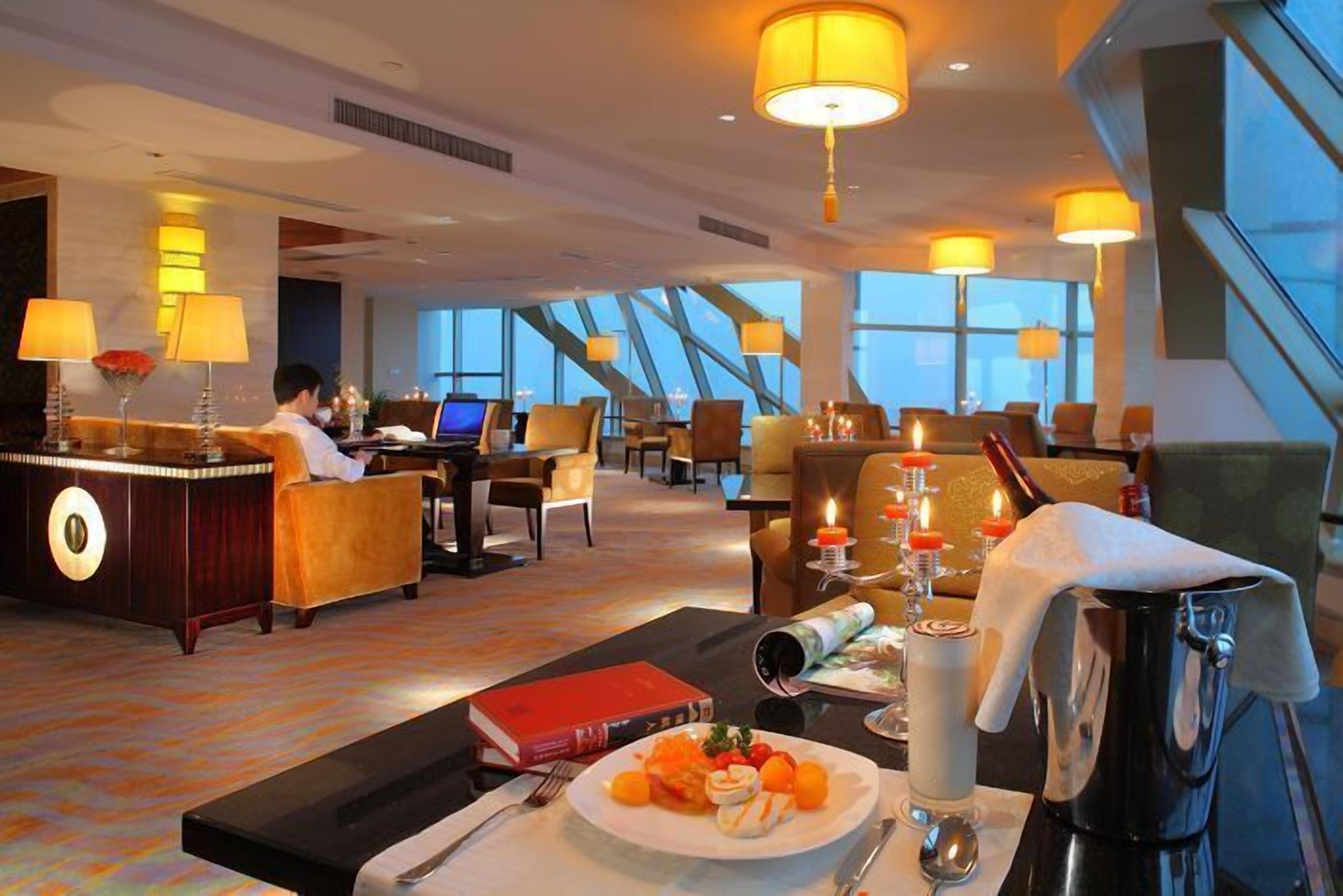 Vestíbulo de hotel con recepción, zona de estar y amplias ventanas con vistas.