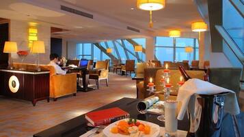 A hotel lobby with a reception desk, seating area, and large windows offering a view.