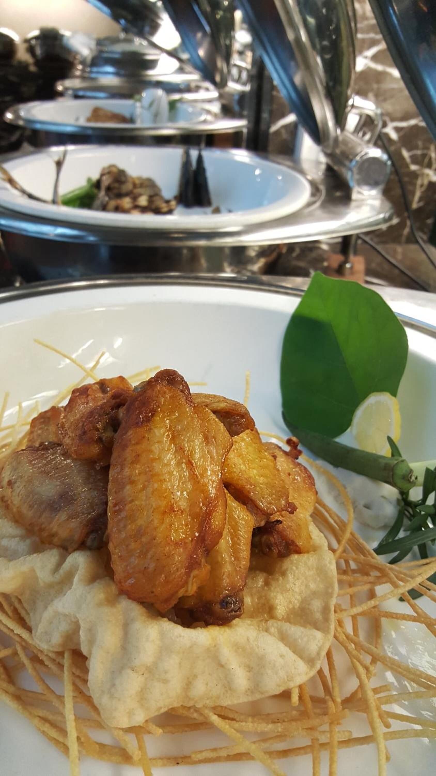 A plate of fried chicken with wedges and a lemon wedge on a table.