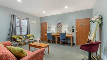 A hotel room with a seating area, a desk, and a mirror.
