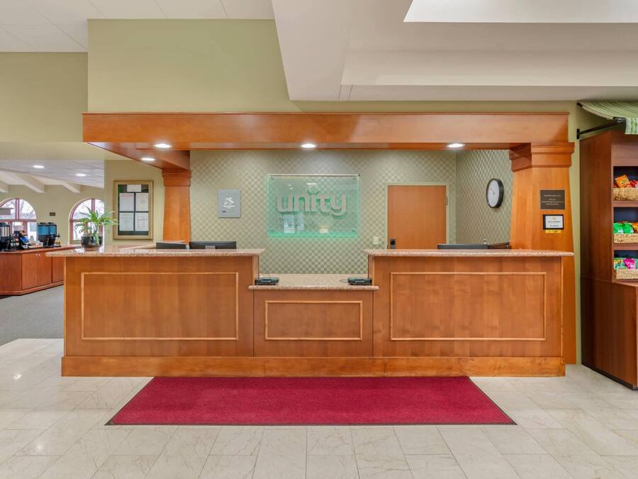 A reception desk with a 'unity' sign, a clock, and a red carpet.