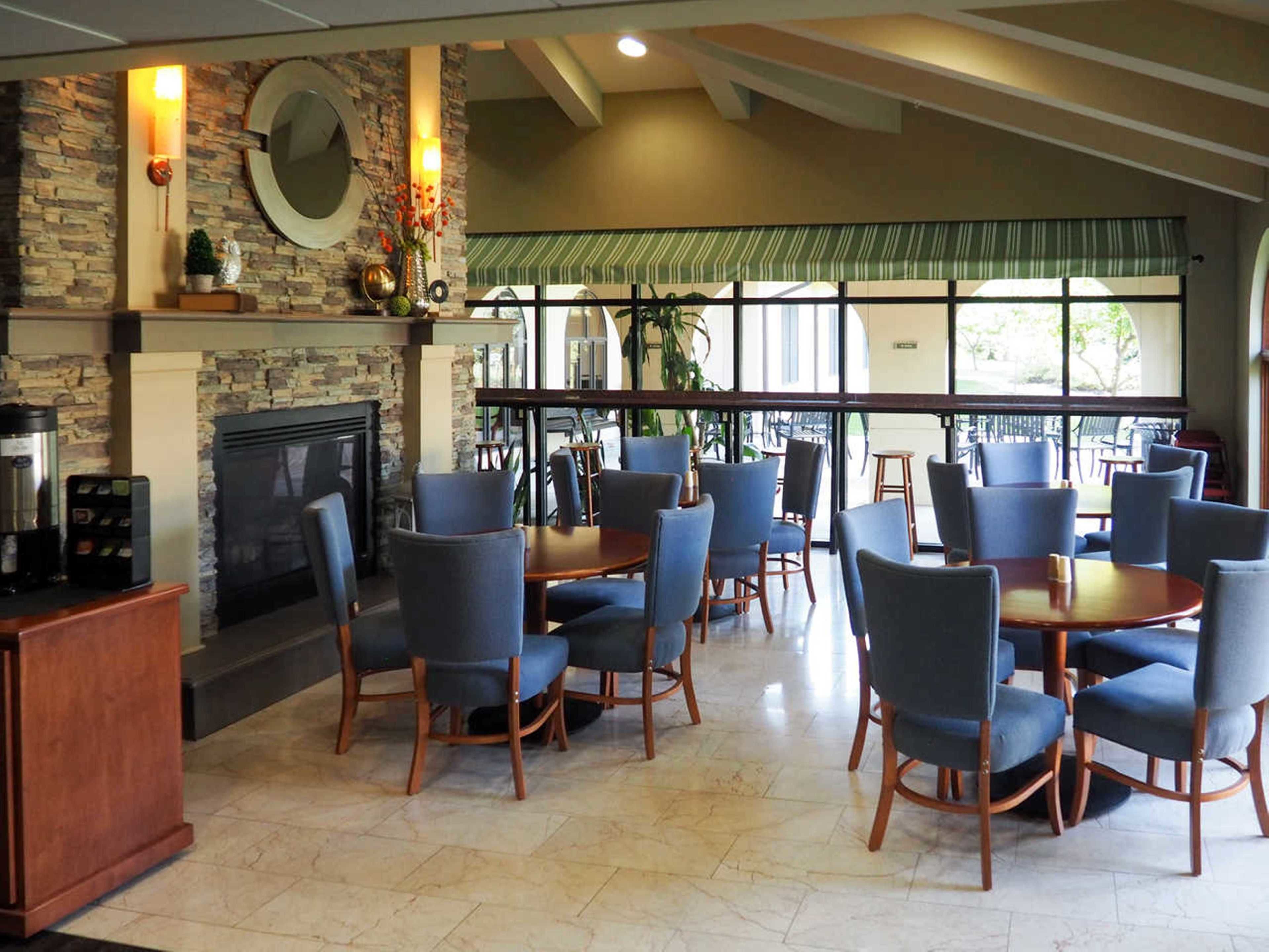 A restaurant with stone walls, a fireplace, and blue chairs.