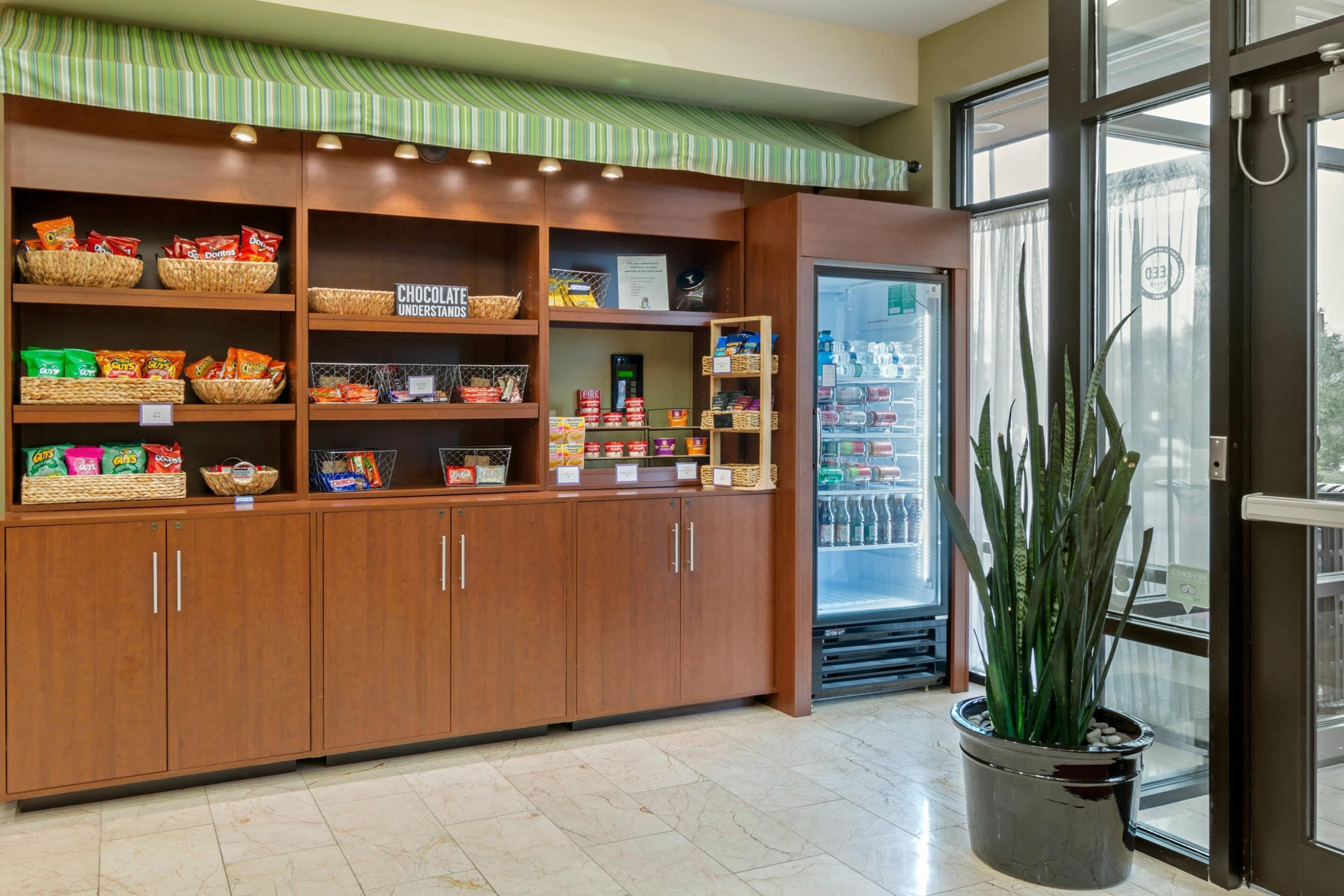 A snack bar with shelves stocked with various snacks and a refrigerator.