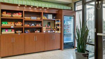 A snack bar with shelves stocked with various snacks and a refrigerator.