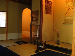 A traditional Japanese room with tatami flooring, a shoji screen, a wooden chair, and a vase with flowers. - Yoshi-Ima (Kyoto)