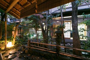 A traditional Japanese garden with stone lanterns, bamboo fences, and a variety of plants. - Yoshi-Ima (Kyoto)