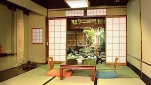 Um quarto japonês tradicional com tatames, uma mesa baixa e portas deslizantes que dão para um jardim.