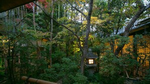 Um jardim japonês tradicional com lanternas de pedra, bambu e vegetação exuberante.