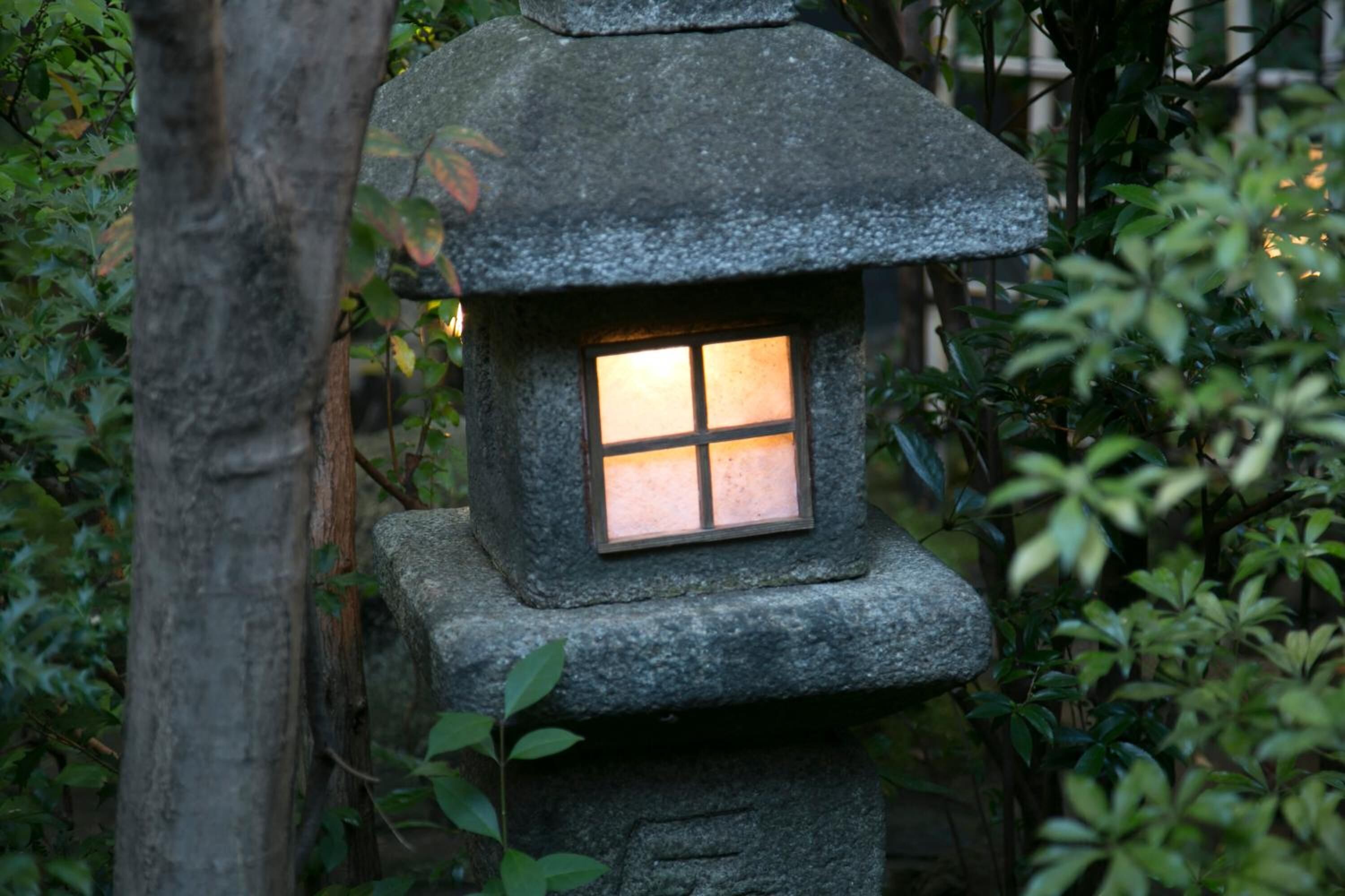 A stone lantern with a window, surrounded by foliage.