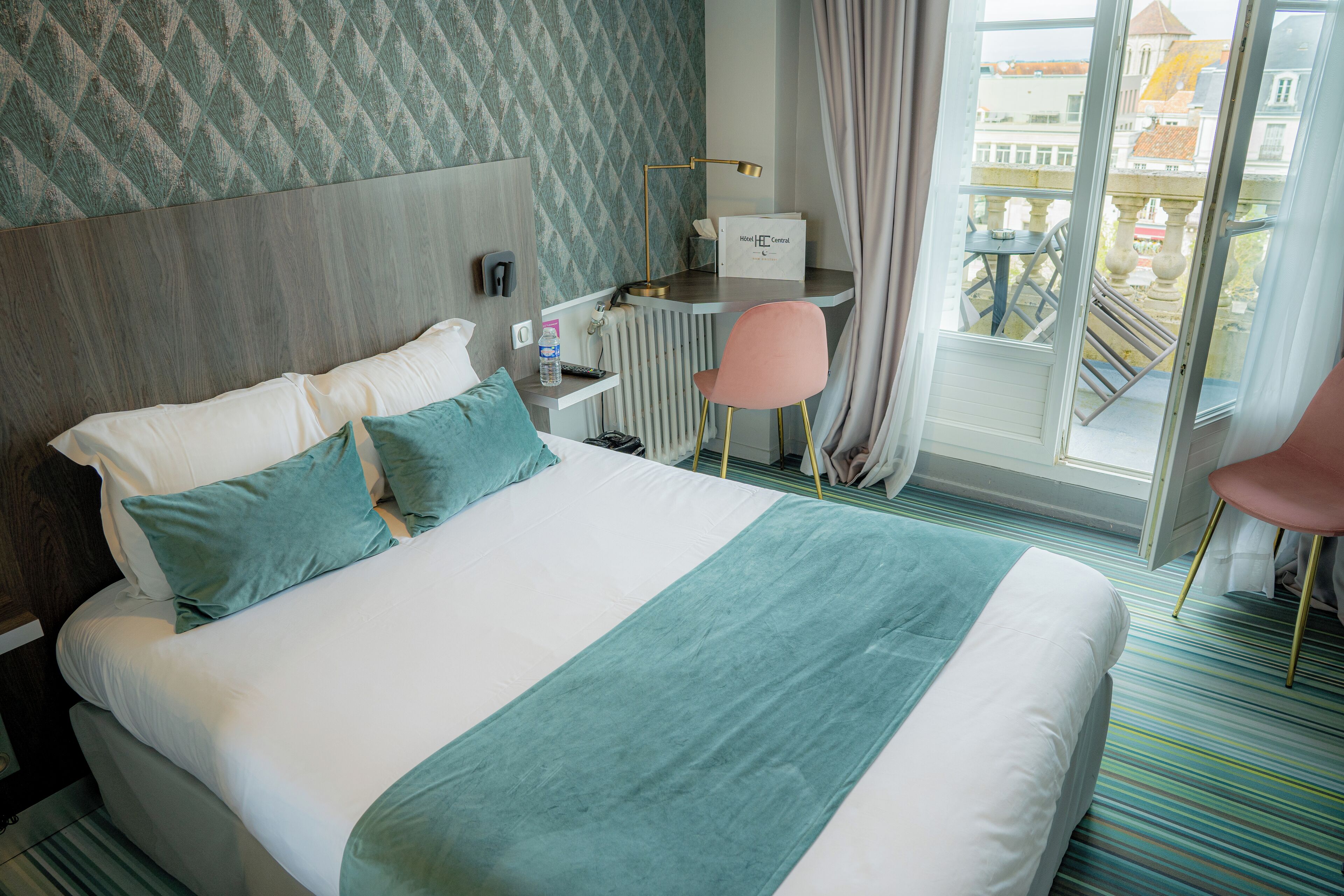 Une chambre d’hôtel avec un lit, un bureau, une chaise et une vue sur l’extérieur.