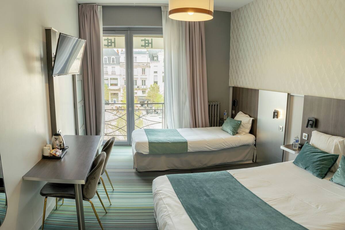A hotel room with two beds, a desk, and a chair.