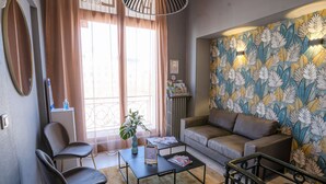 A living room with a sofa, two armchairs, a coffee table, and a patterned wall. - Hotel Central (Poitiers)