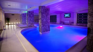 Une piscine intérieure moderne, dotée de piliers en pierre, d’un plancher plat et d’un plafond plat.