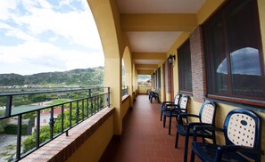 A balcony with chairs and a view of a green landscape and hills. - A Nuciara Park Hotel & Wellness Center (Furci Siculo)