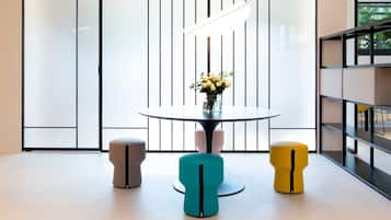 Ein modernes Interieur mit einem runden Glastisch, drei Barhocker und einer Blumenvase.