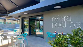 An outdoor pool bar area with turquoise chairs and tables, a glass door entrance, and a sign reading "rivier pool bar".