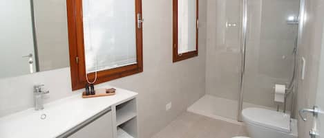 A modern bathroom with a shower, toilet, and vanity.