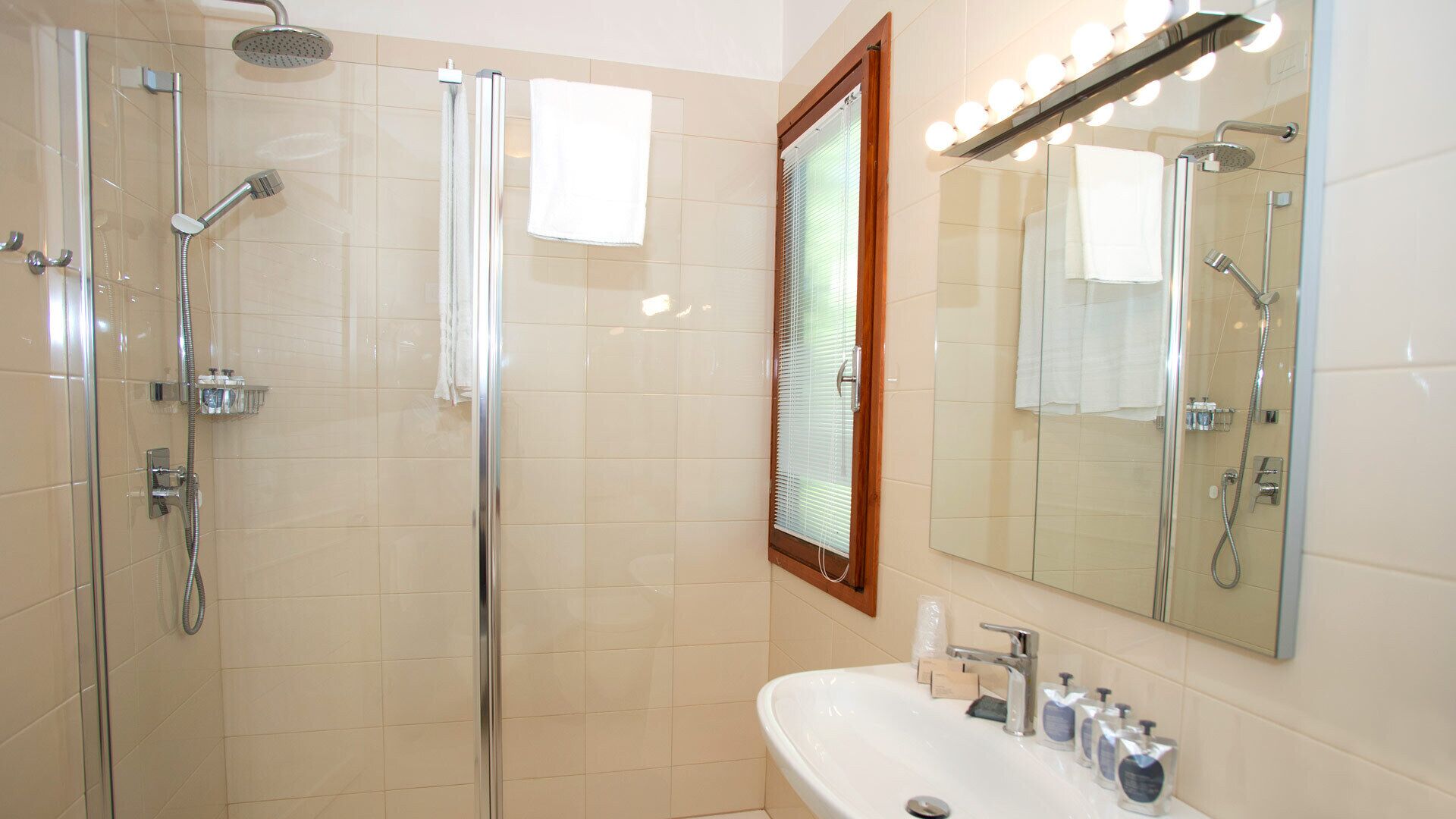 Un baño moderno con ducha envuelta en vidrio, tocador con espejo y lavabo.