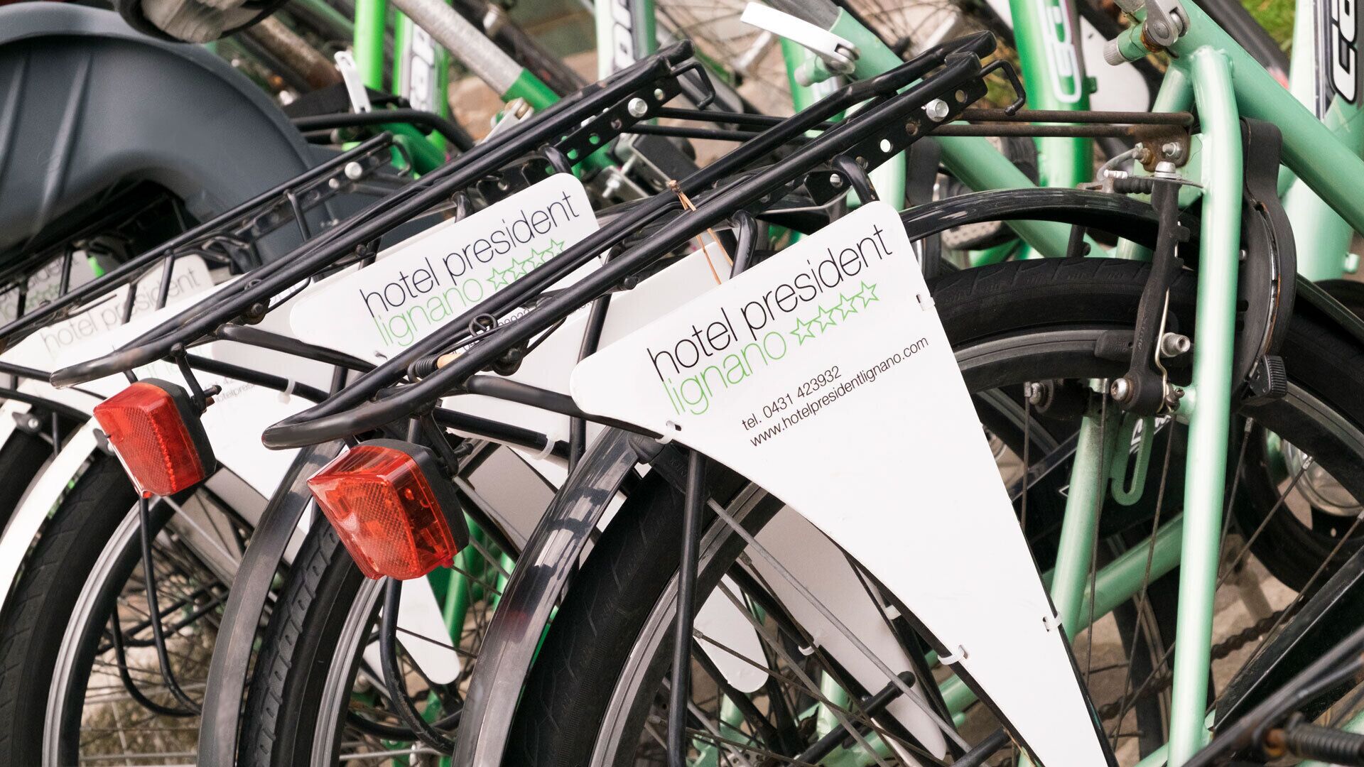 A bicycle with a white sign that reads "hotel president" and "lignano".