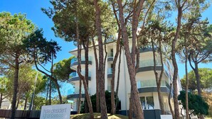 A multi-story hotel with a modern design, surrounded by tall trees.