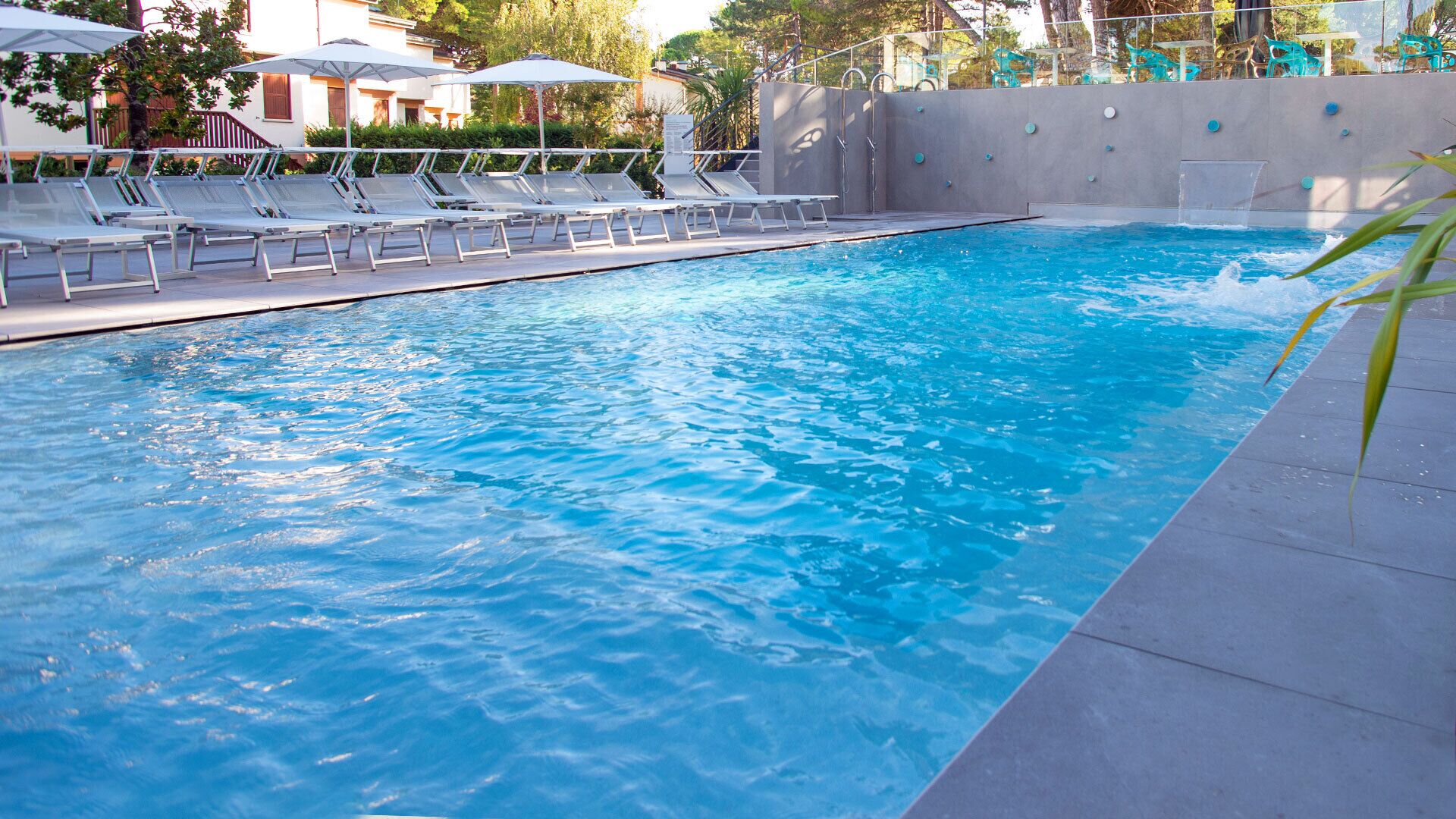 Una piscina con lettini e ombrelloni.