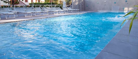Una piscina con tumbonas y sombrillas.