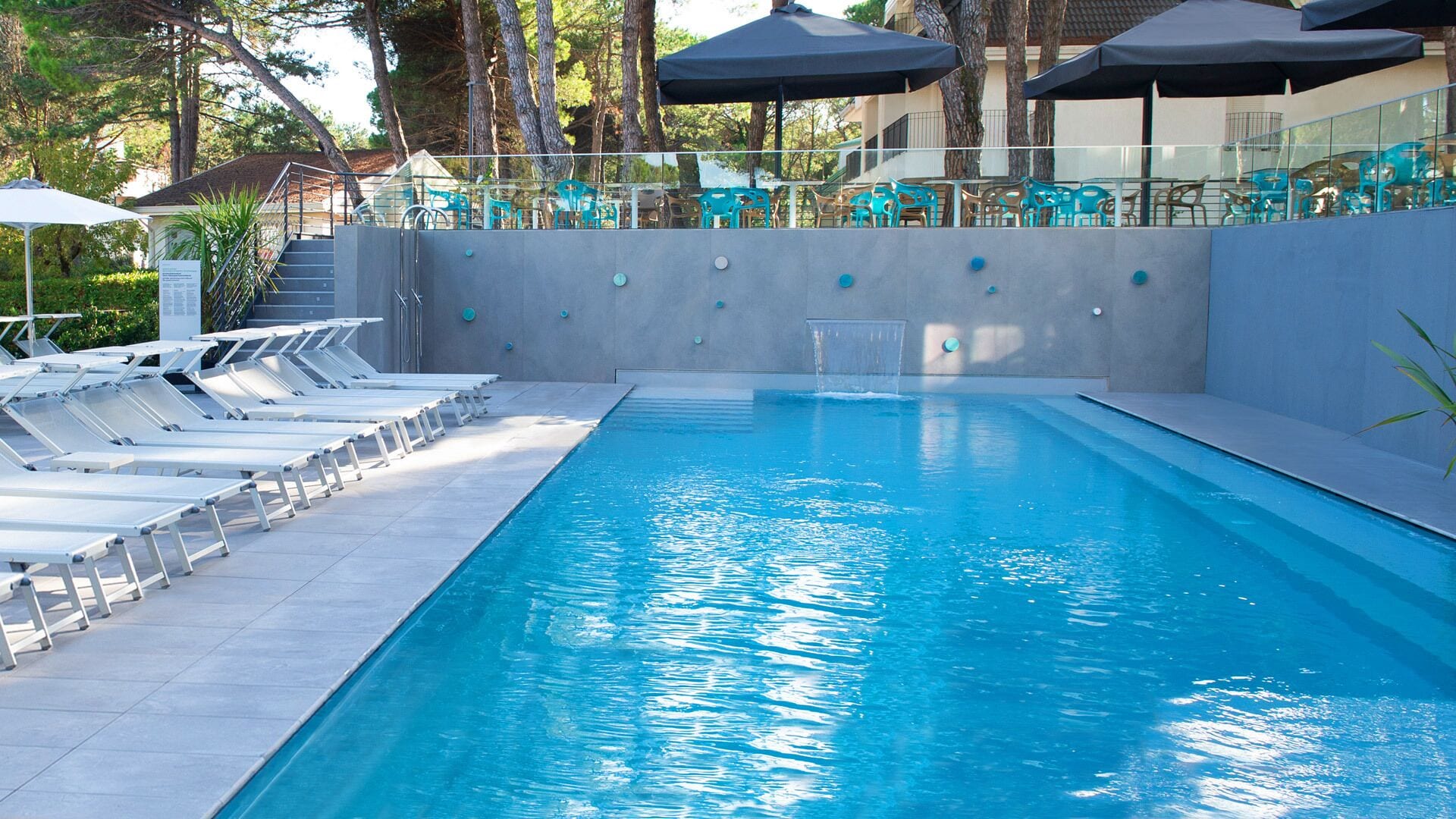 A swimming pool with lounge chairs and umbrellas.