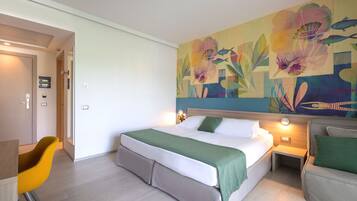 Une chambre d’hôtel avec un lit, une chaise, une table de chevet et un mur orné d’un tableau représentant des motifs floraux.