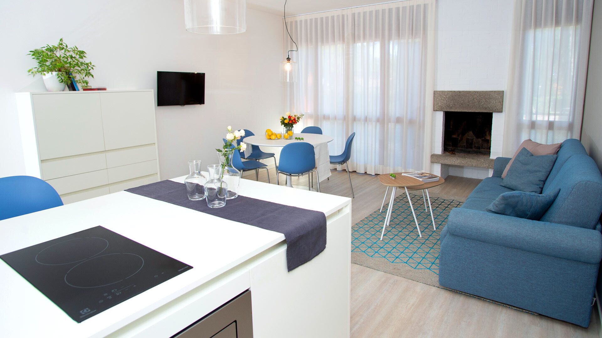 Una sala de estar moderna con comedor, chimenea y televisor montado en la pared.