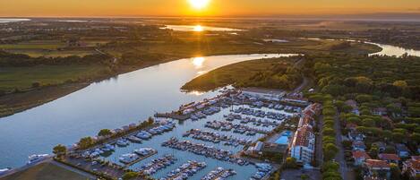 An aerial view of a marina with numerous boats docked, surrounded by residential buildings and greenery.