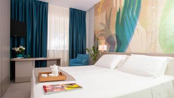 Habitación de hotel con cama, escritorio, silla, televisor y un cuadro en la pared.