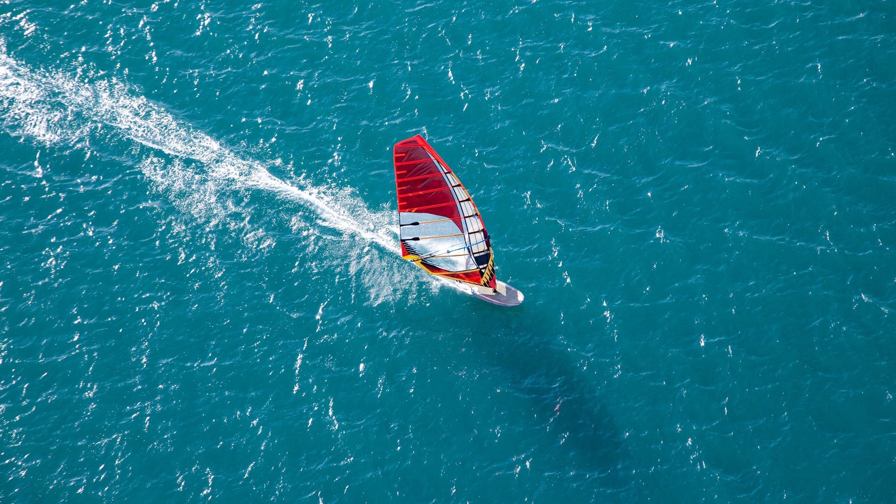 A person windsurfing on a turquoise sea.