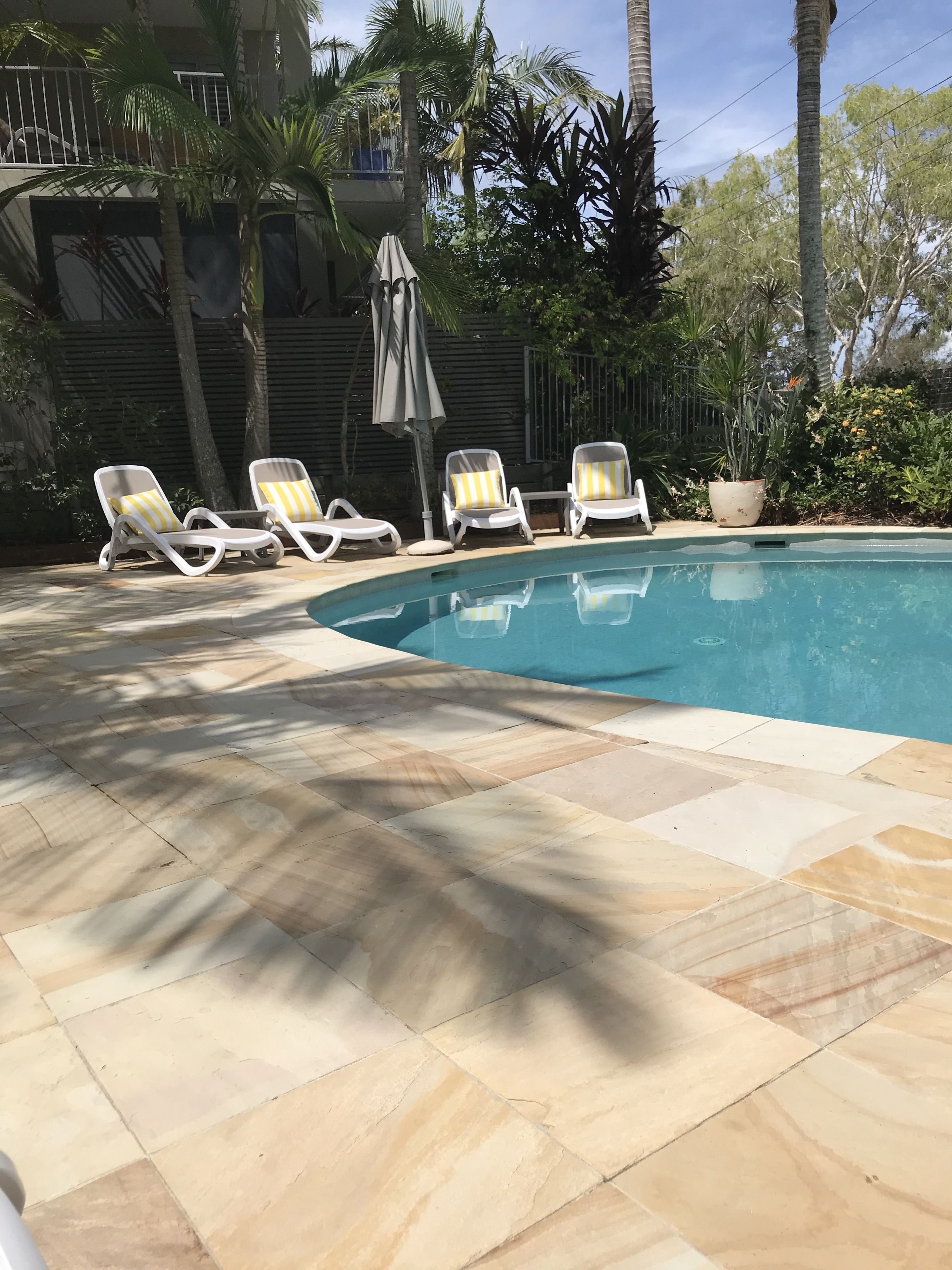 Una piscina con sillones de descanso y un deck empedrado.