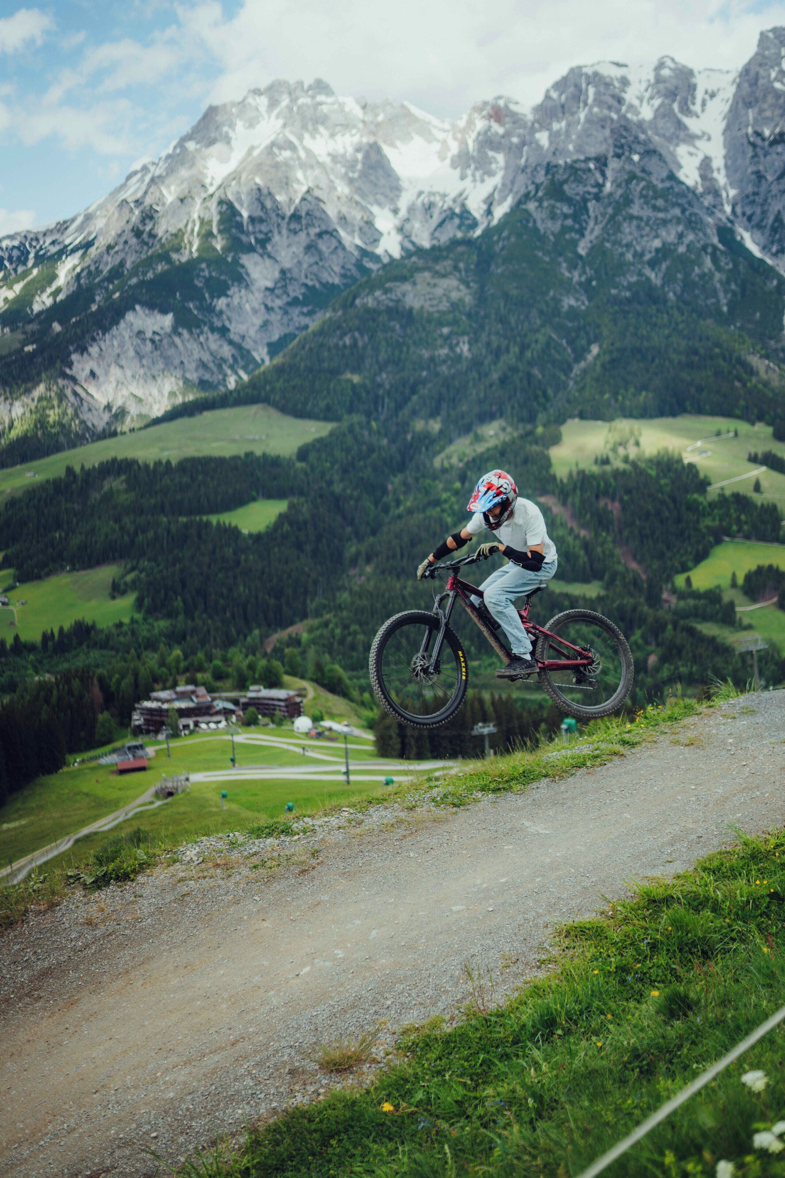 A mountain biker on a dirt path with a mountainous backdrop.