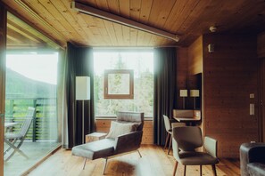 A modern interior with a wooden ceiling, a sofa, a chair, and a desk. - Forsthofalm (Leogang)
