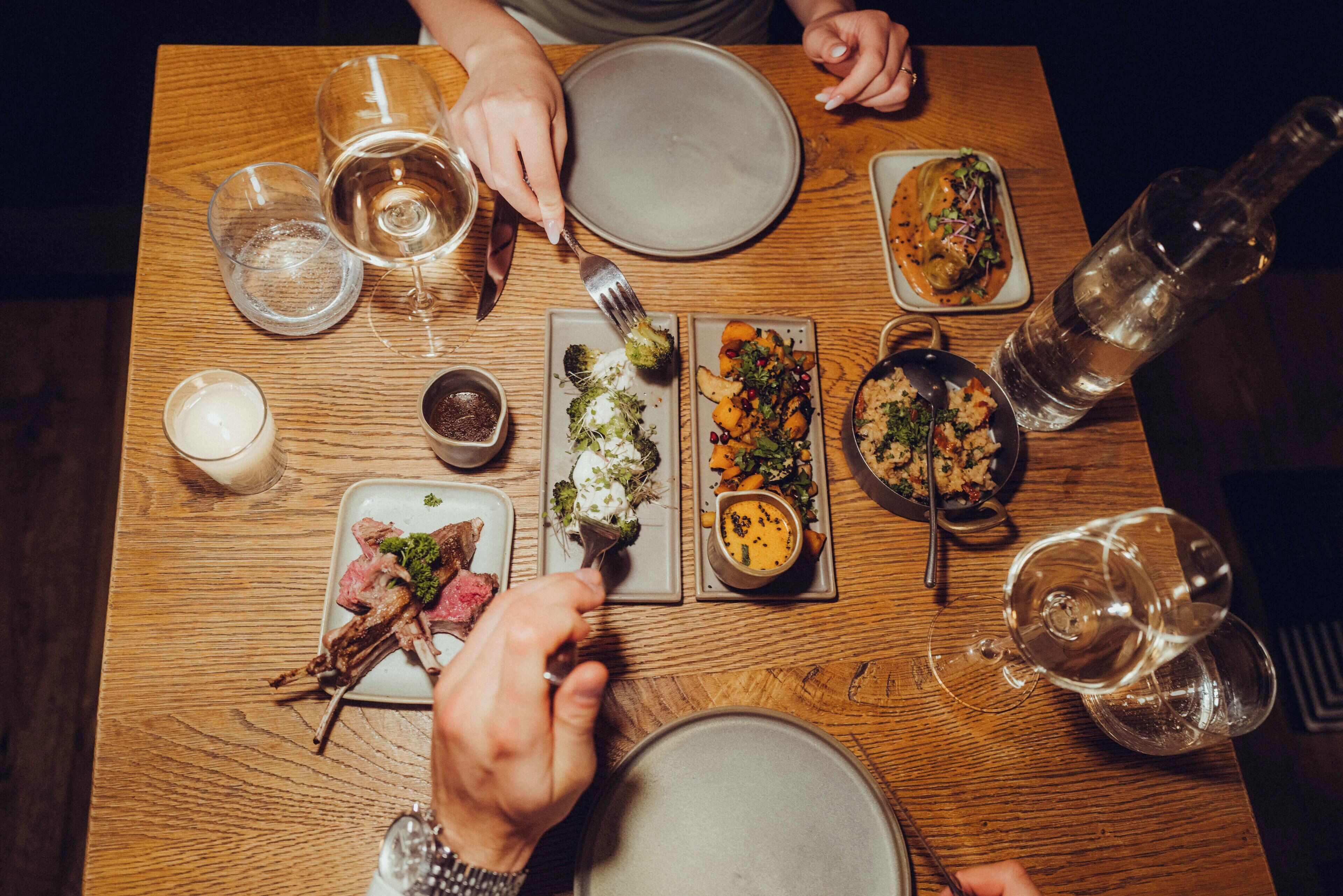 A wooden dining table with various dishes and glasses of water.